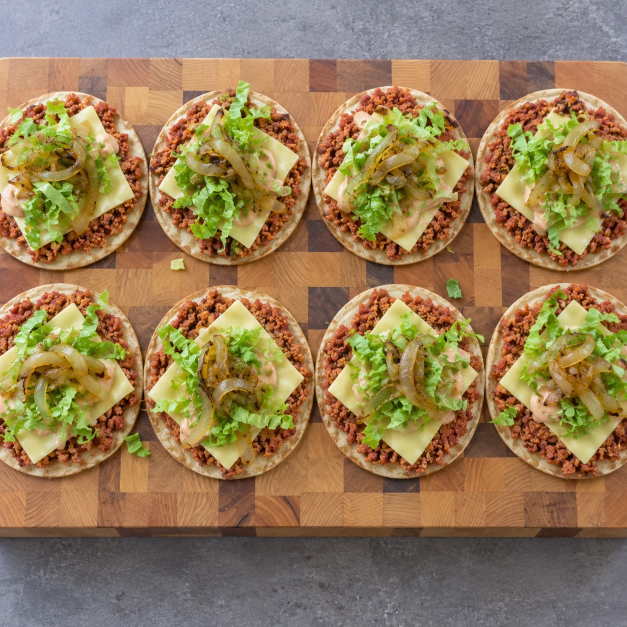 Salade émincée et oignons dorés sur des petits tacos ouverts.