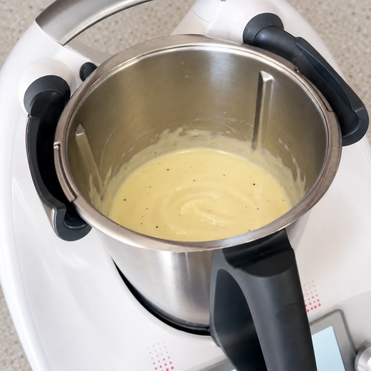 Sauce fromagère végétale lisse blanc crème avec de rares points de poivre dans le bol métallique ouvert.