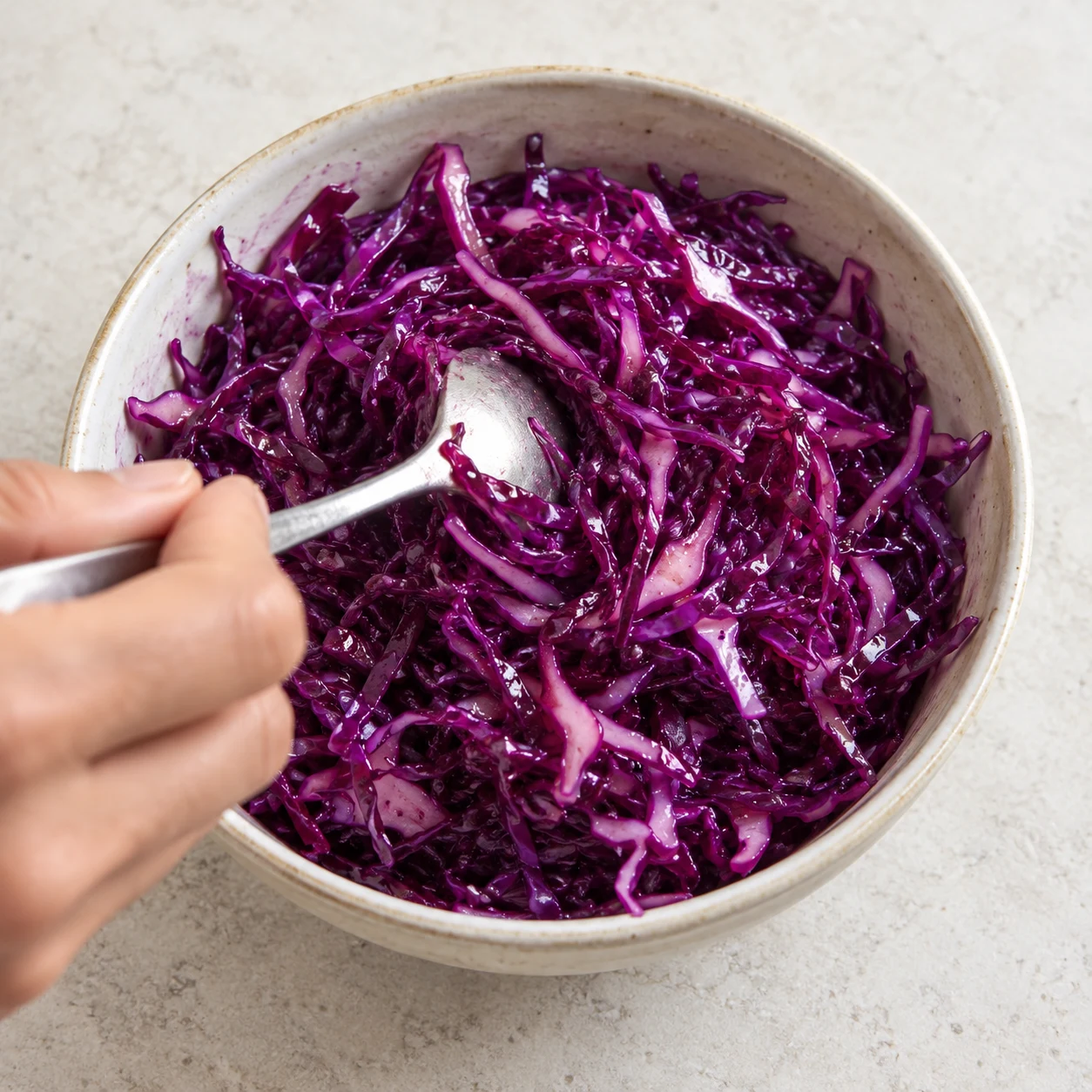 Mélanger à la cuillère la salade de chou rouge avec la sauce, texture fine et humide ; sans graines de sésame.