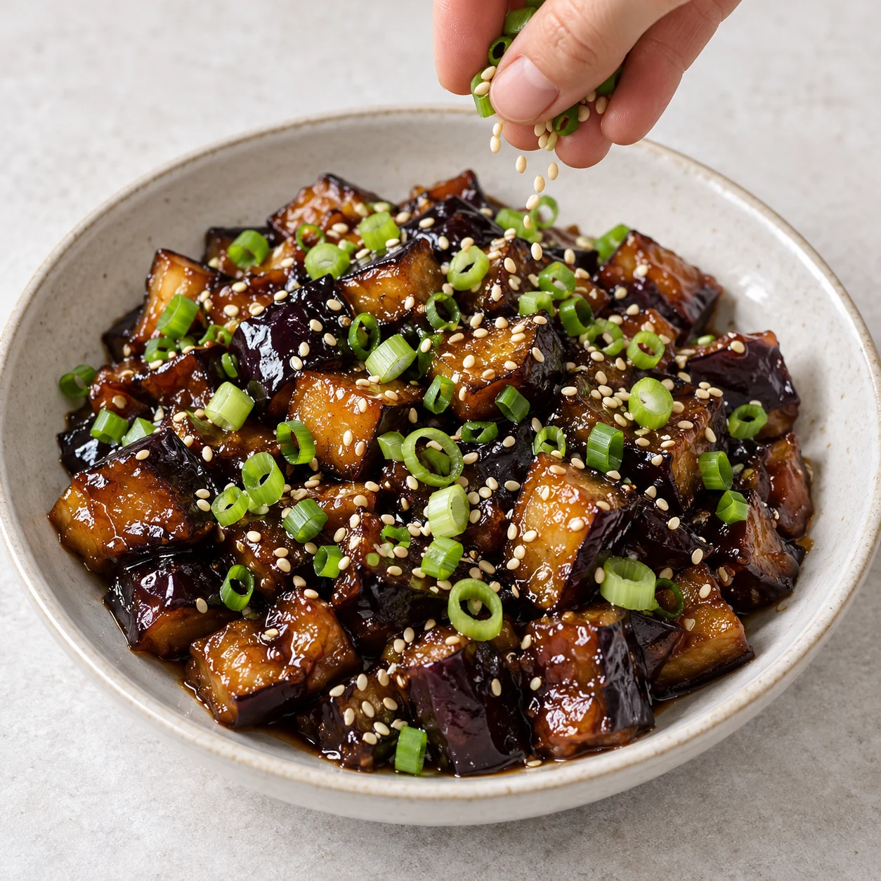 Aubergines brillantes garnies d’oignon nouveau et sésame.
