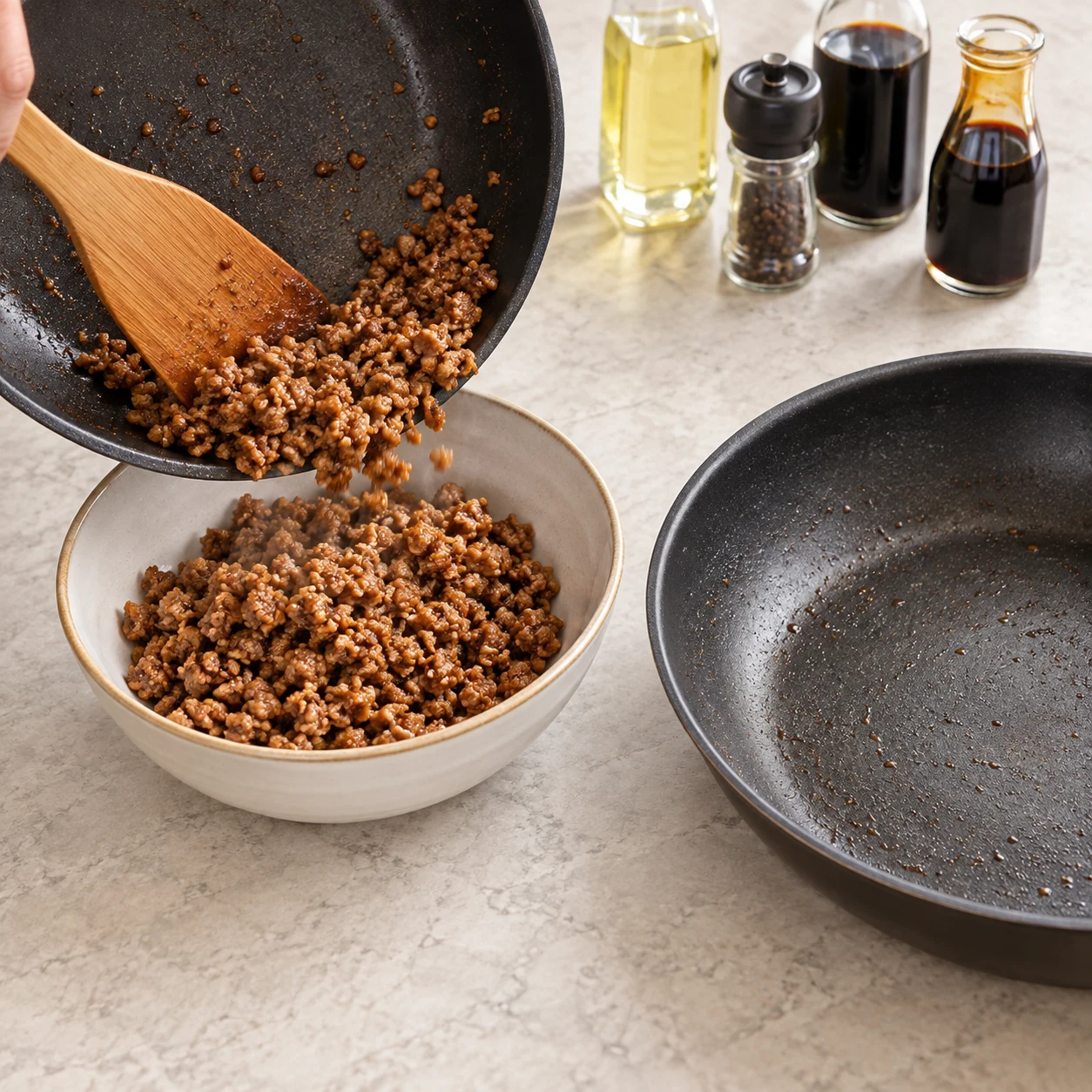 Transférez le haché de soja chaud dans un bol, séparé de celui des pois chiches. Résultat visuel : Le haché est réservé dans son bol et la sauteuse est libre. Montrer seulement les ingrédients de cette étape, sur plan de travail pierre pâle ; pas de viande, pas d’œuf, pas de tofu.