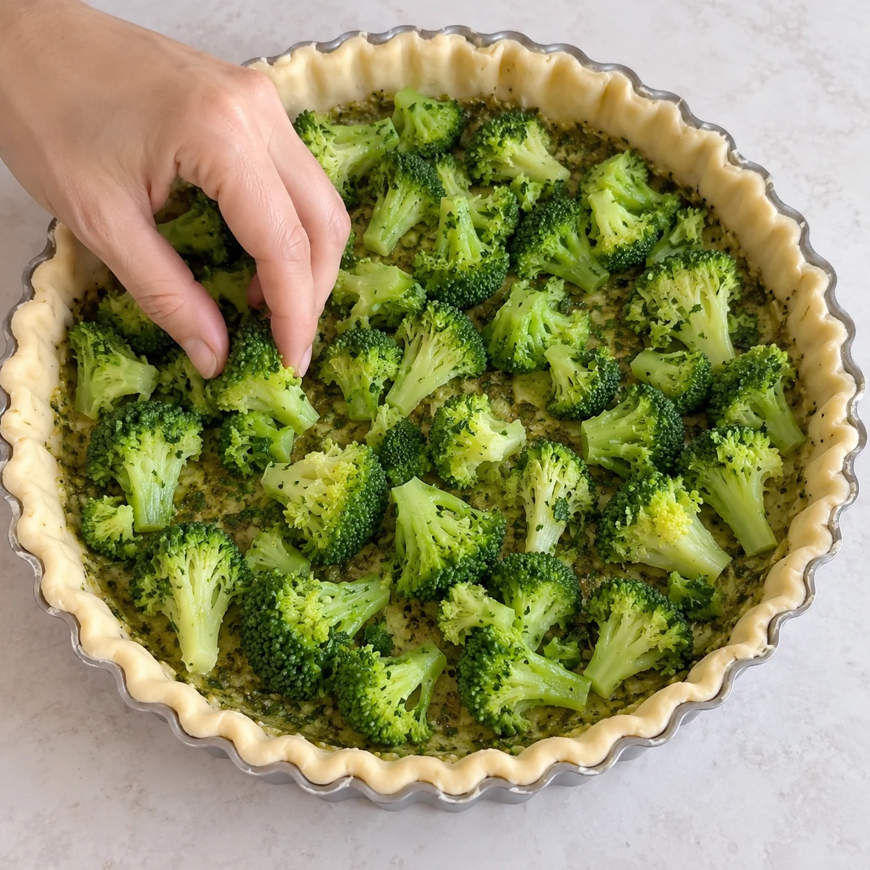 Répartir le brocoli : Les fleurons couvrent le fond sans former un gros tas au centre. Ingrédients finaux uniquement, une seule action, photographie carrée réaliste.