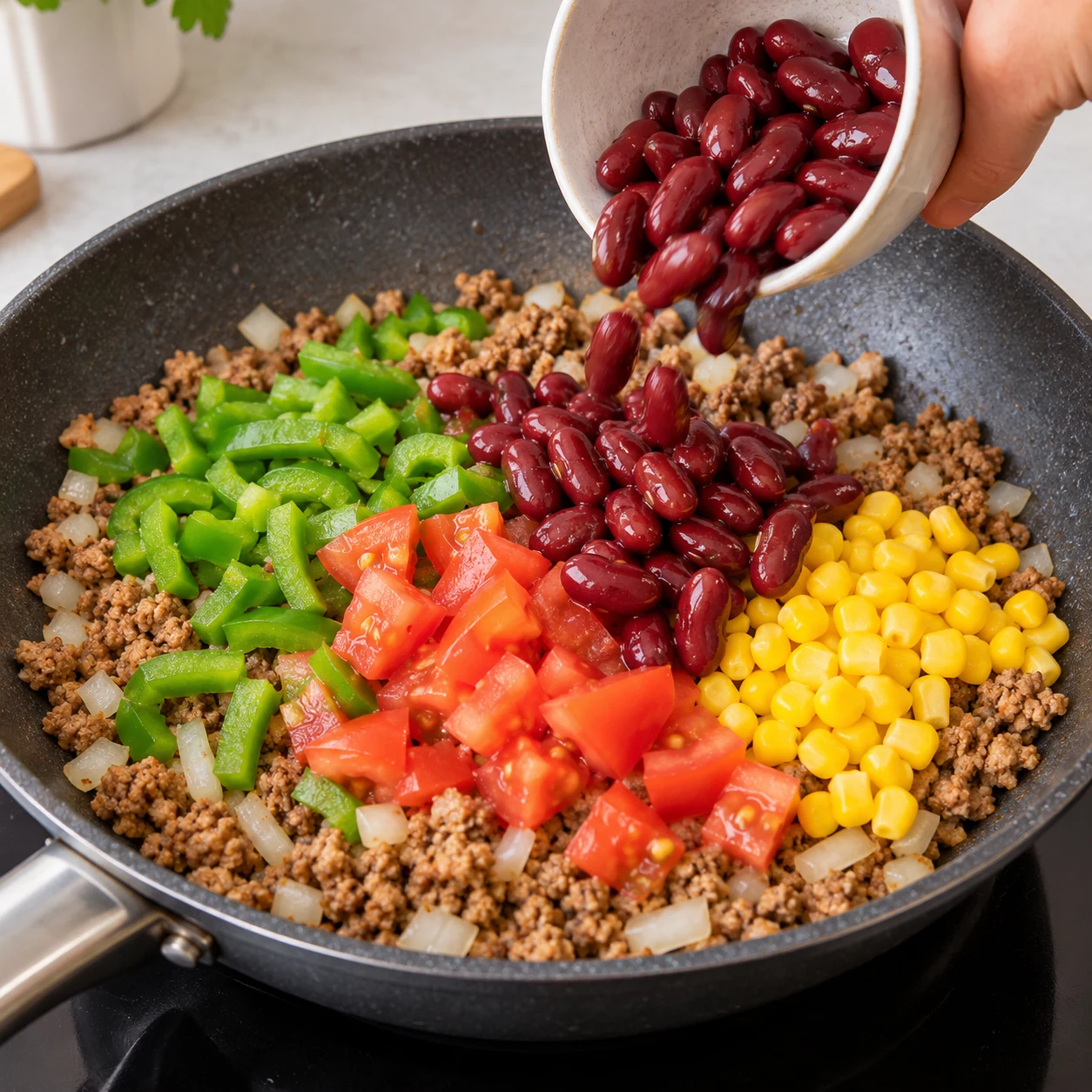 Haricots rouges ajoutés dans la poêle, légumes encore en morceaux distincts.