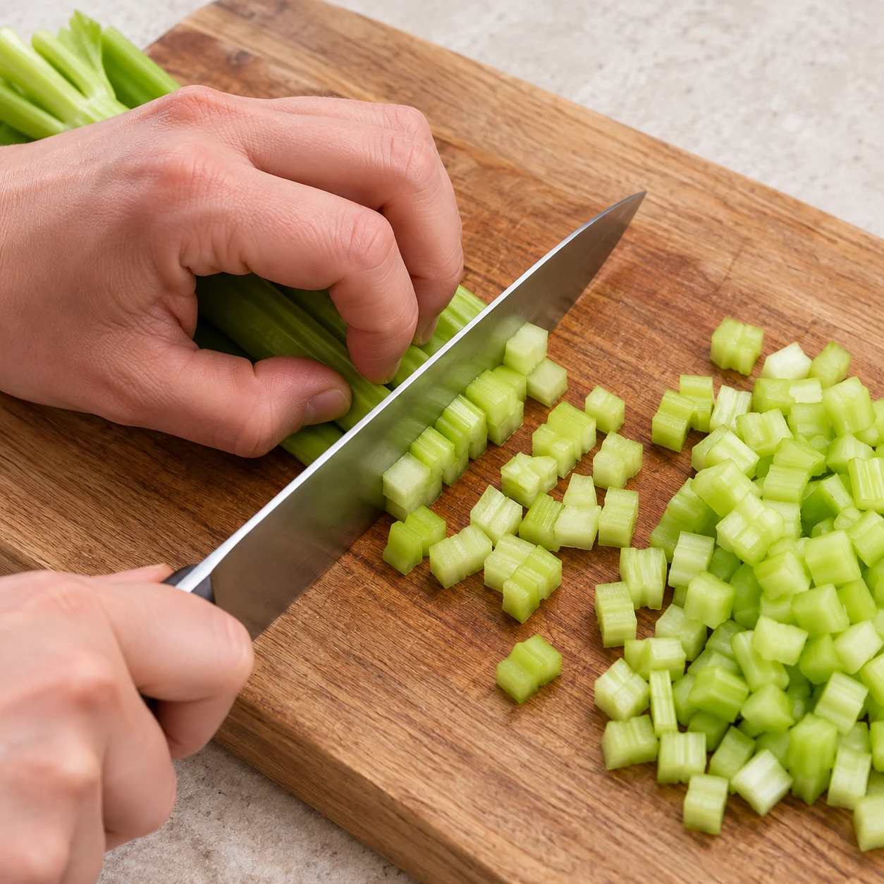 Couteau en action sur branche de céleri vert, petits dés, doigts protégés.