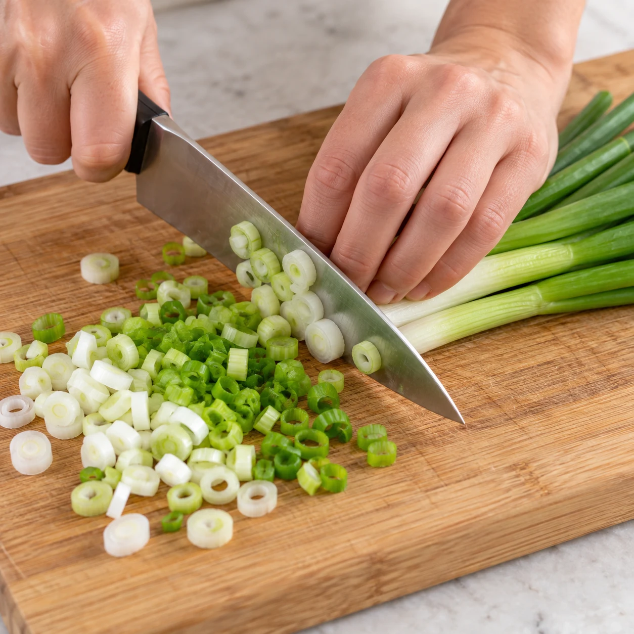 Découpe sûre d’oignons nouveaux blancs et verts.