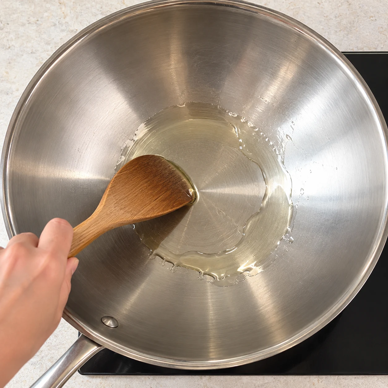 Une petite quantité d’huile de tournesol chauffe seule dans un wok neutre, aucun autre ingrédient.