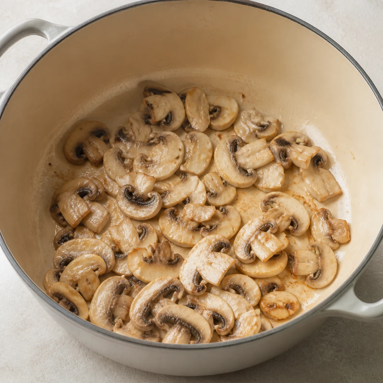 Champignons de Paris dorés dans une cocotte, lumière naturelle.
