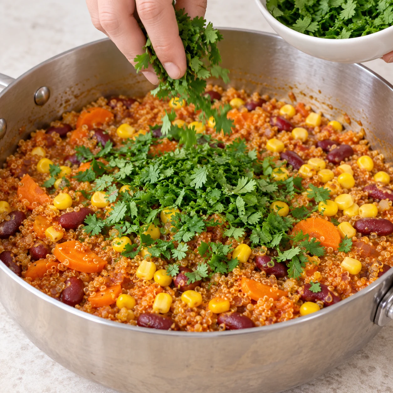 Coriandre hachée verte déposée sur quinoa cuit avec maïs, carottes et haricots.
