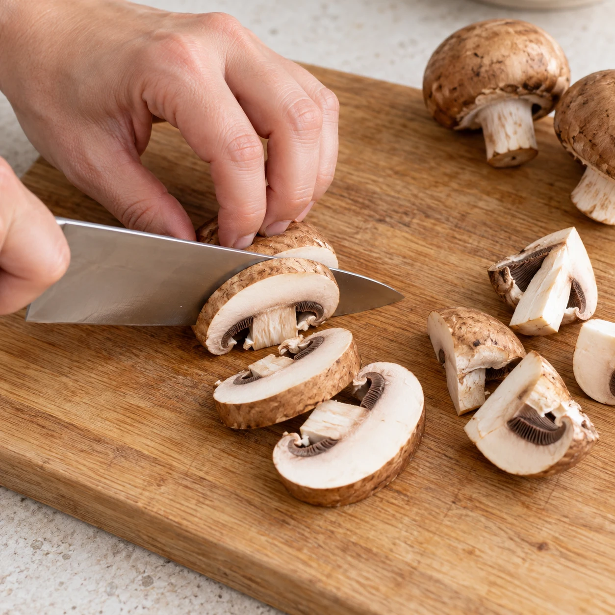 Couteau coupant un seul champignon brun, main en griffe sûre, lamelles épaisses et quartiers visibles.
