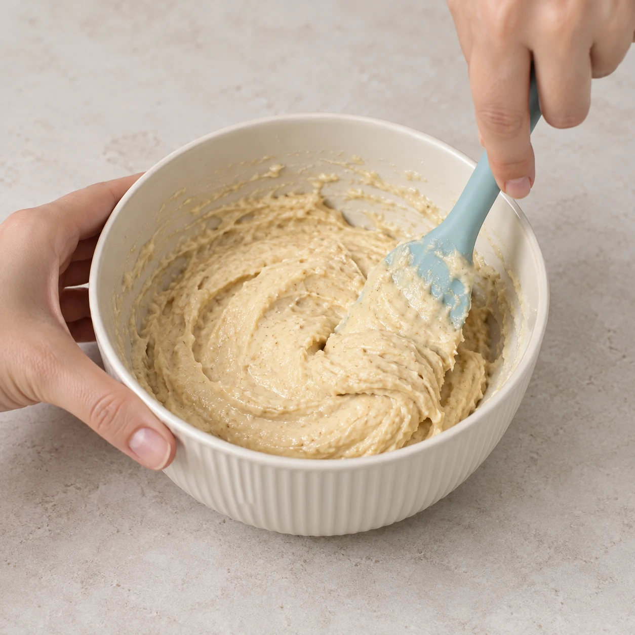 Spatule mélangeant une pâte beige épaisse dans un bol, sans chocolat.