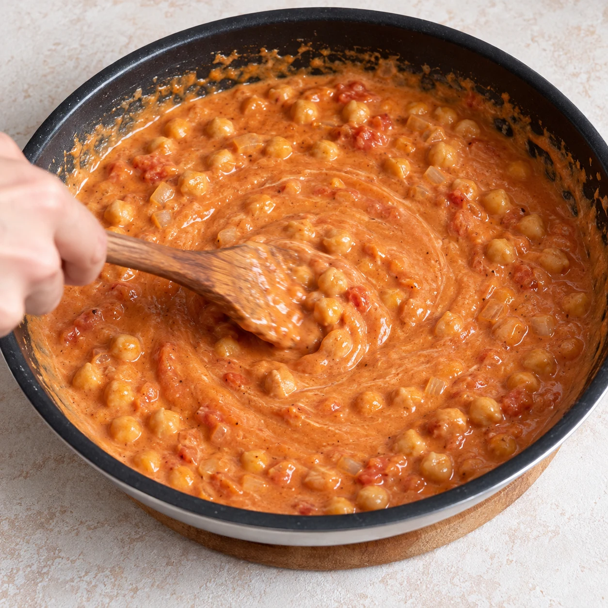Mélangez le contenu de la poêle pour incorporer le beurre de cacahuète à la tomate et au lait de coco. Une seule scène et une seule phase ; ne montrer que les ingrédients autorisés à cette étape.