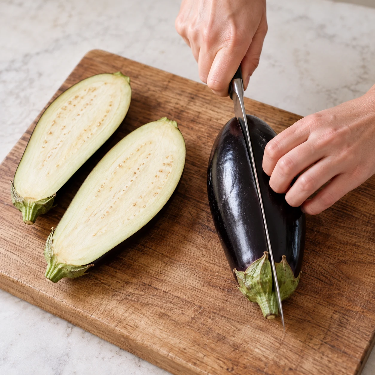 Quatre demi-aubergines montrent leur chair claire et leur peau intacte.