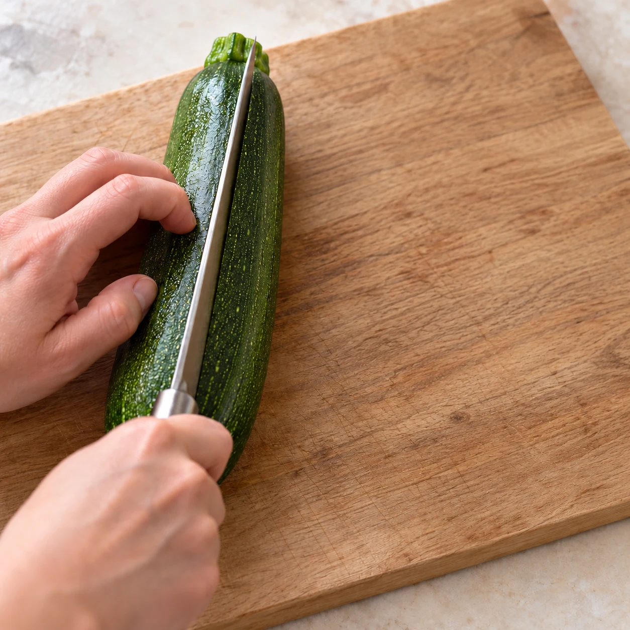 Découpe sûre d’une courgette verte entière dans la longueur en deux moitiés, sur une planche stable ; aucune farce.