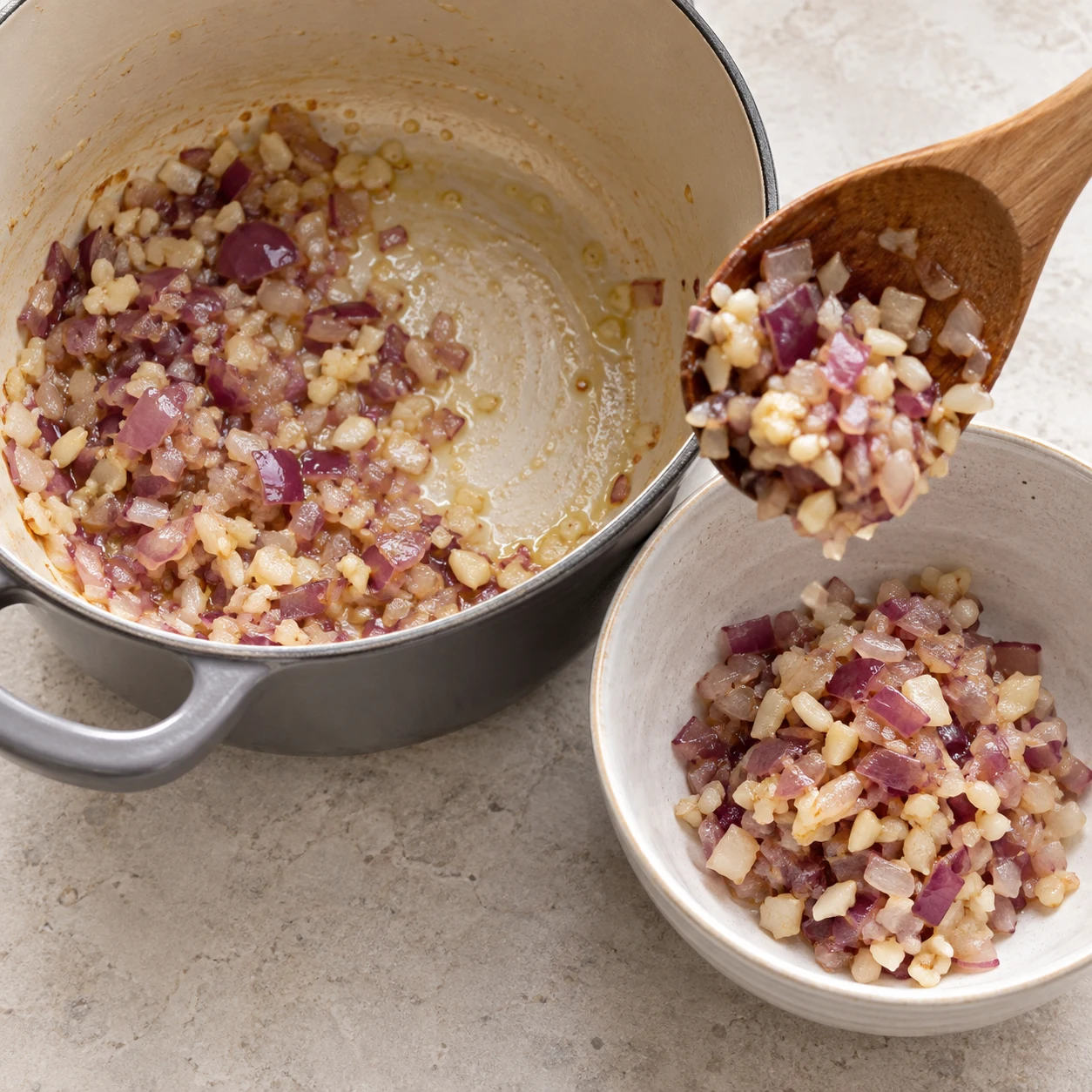 Une seule phase : Prélevez la moitié du mélange d’ail et d’oignon et réservez-la pour les boulettes. État attendu : Une moitié est réservée, l’autre reste dans la casserole. Sans texte, sans personne identifiable, uniquement les ingrédients de cette étape.