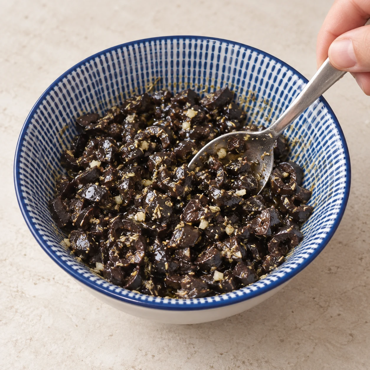Assaisonner les olives. Les morceaux noirs sont uniformément enrobés d’huile et d’aromates. Respecter la capture source ; chorizo et cheddar uniquement végétaux, aucune autre garniture.