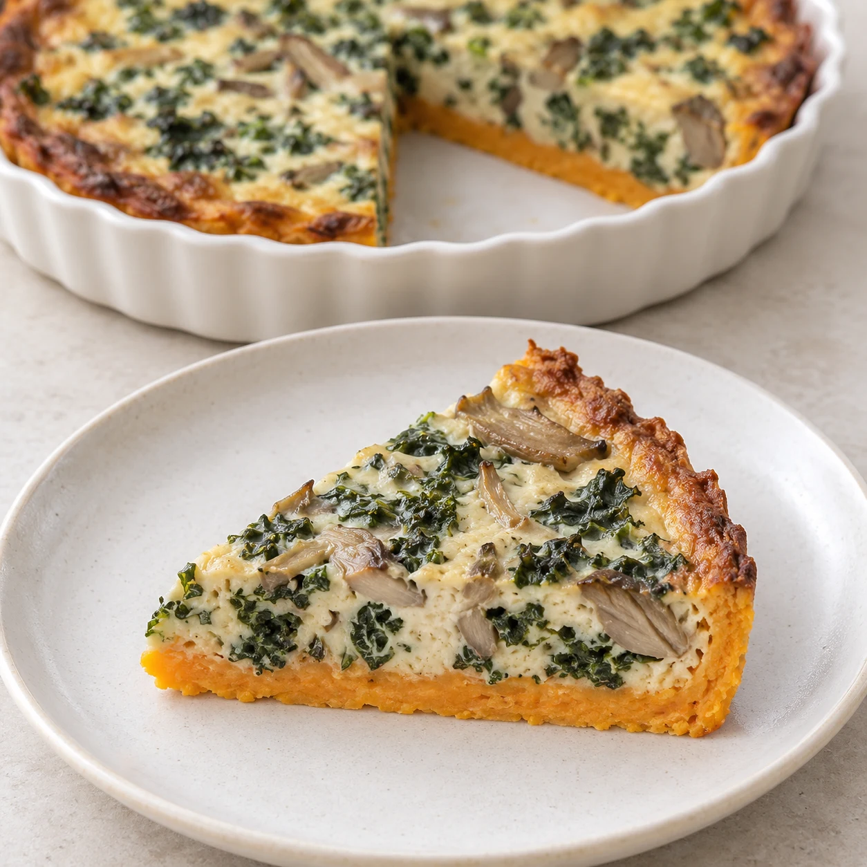 Part de quiche végétale tenue, base orange et garniture beige au kale et aux pleurotes ; aucun fromage.