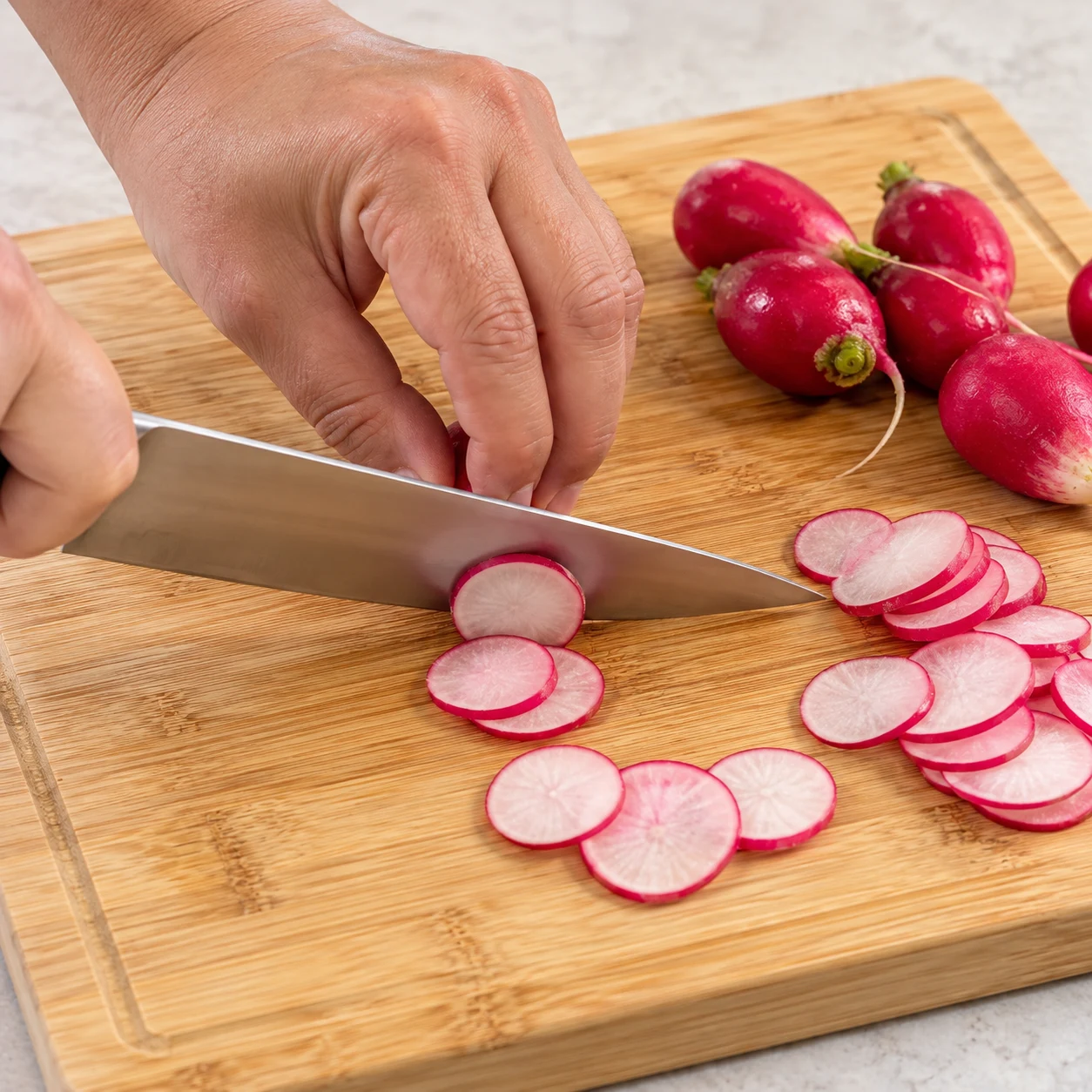 Radis roses en cours de découpe en fines rondelles.