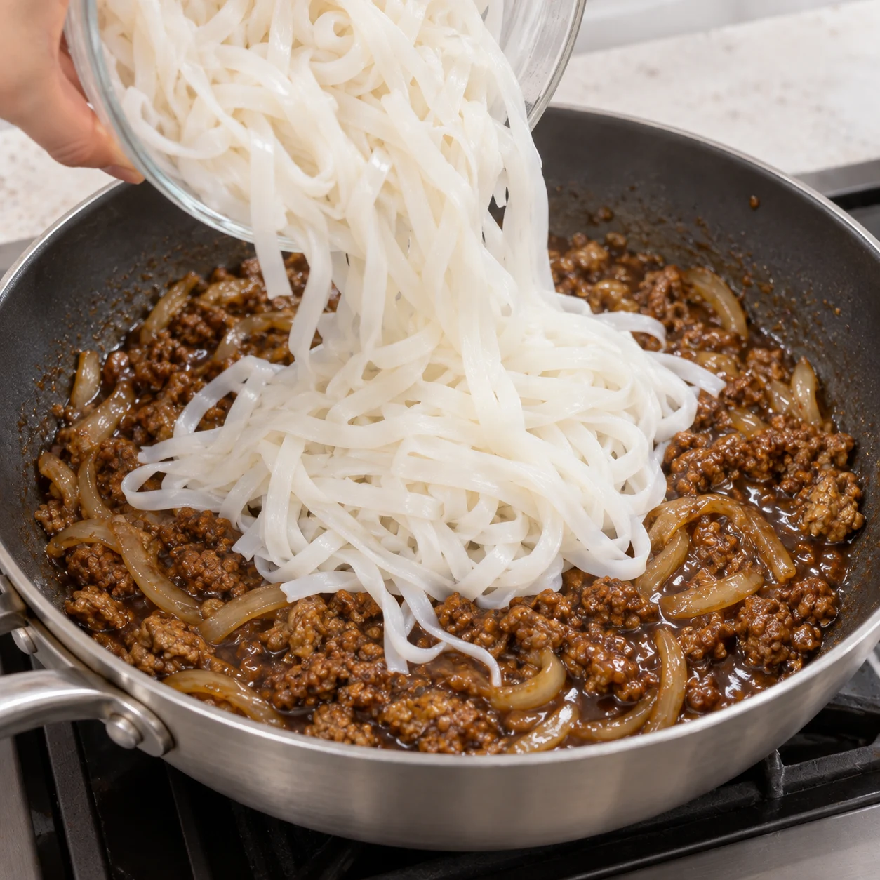 Nouilles de riz cuites déposées sur la garniture en sauce.