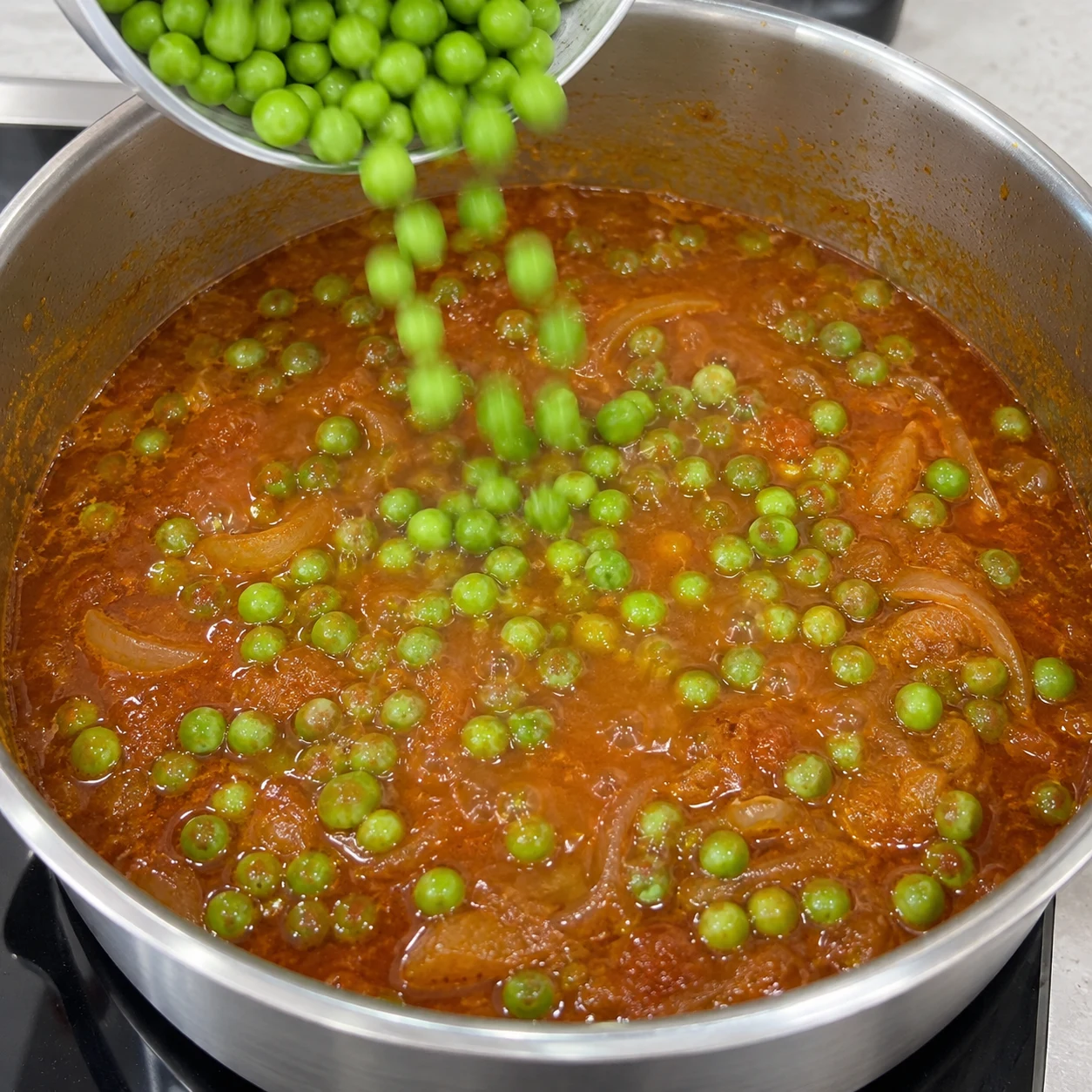 Une seule action : Ajouter les petits pois. Les petits pois sont répartis dans la sauce. Version végétale aux pois chiches, aucune viande, aucun seitan, aucun tofu.