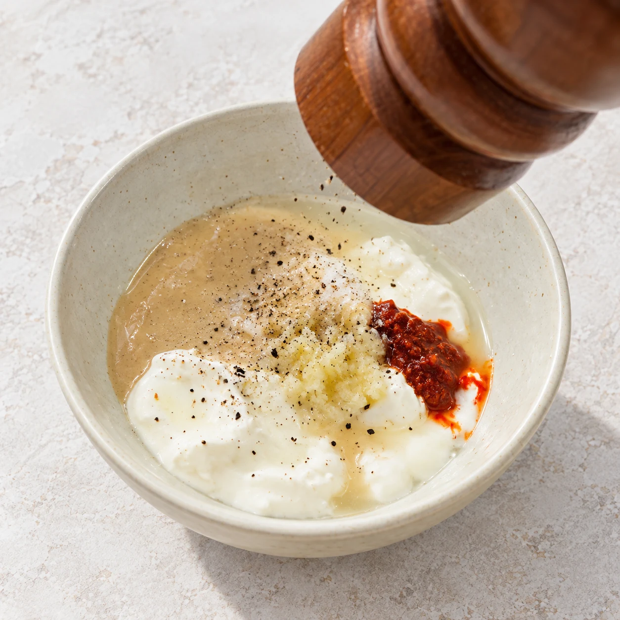 Moulin neutre à poivre au-dessus de la base de sauce avec de petits grains de poivre ; aucun emballage.