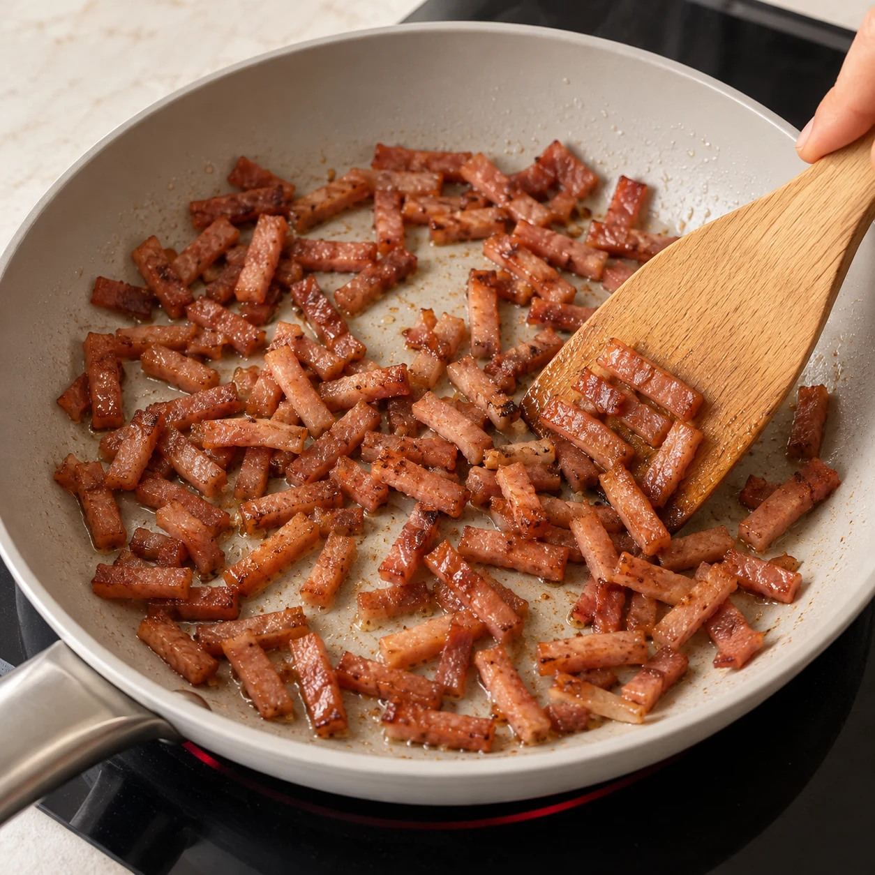 Une spatule retourne uniquement des lardons végétaux fumés dans une poêle.