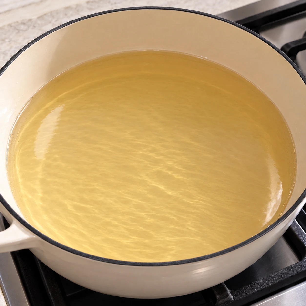 Poêle à bords hauts avec huile de friture seule qui chauffe sur une plaque, sans galette encore ajoutée.
