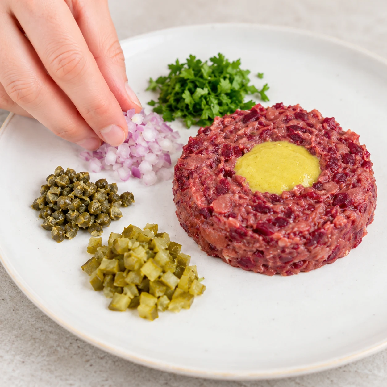 Disposer les condiments : Les quatre condiments sont répartis à côté des tartares.