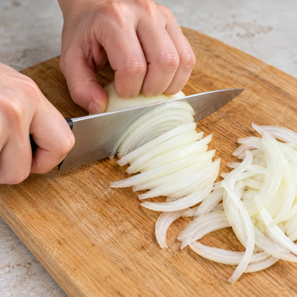 Émincez l’oignon en fines lamelles sur une planche stable. Montrer seulement l’action et cet état de cuisson.