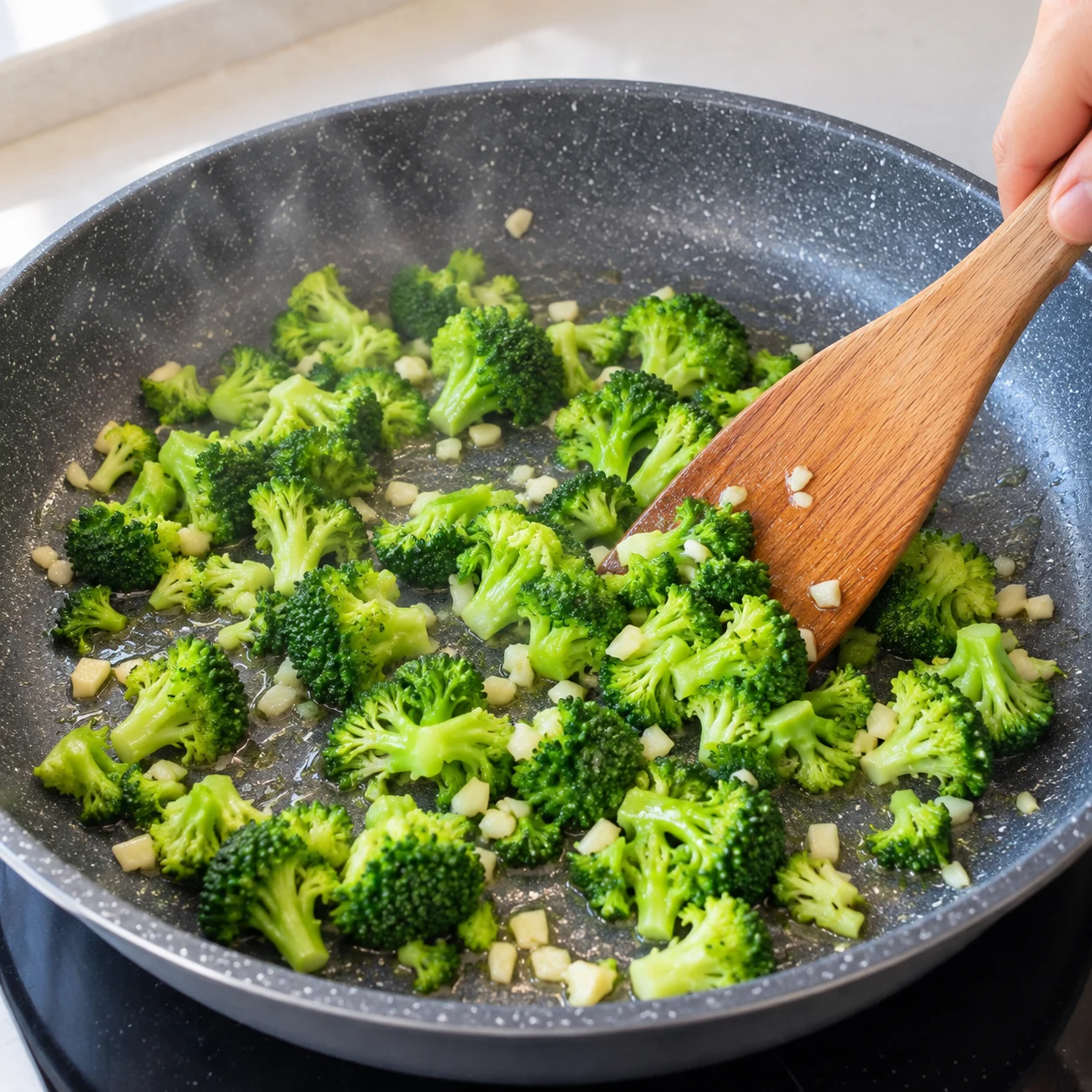 Remuer de petits morceaux de brocoli avec ail et huile dans une grande poêle.