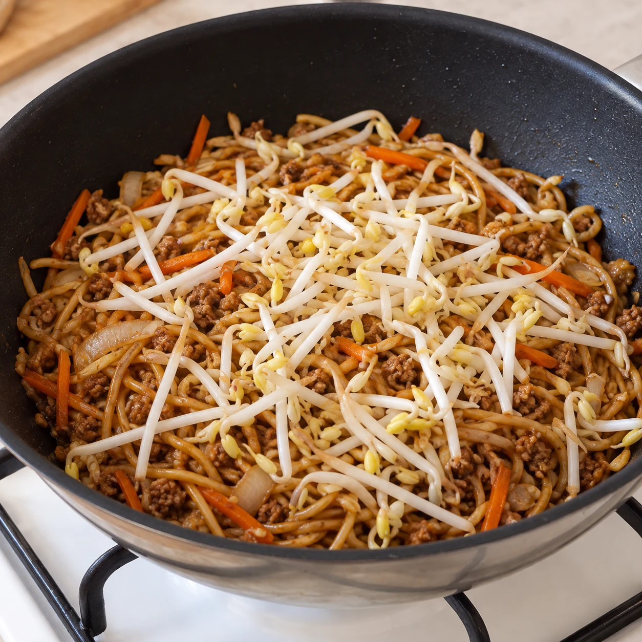 Ajoute les 100 g de pousses de haricot mungo aux nouilles sautées. Résultat : Les pousses sont réparties sur les nouilles.