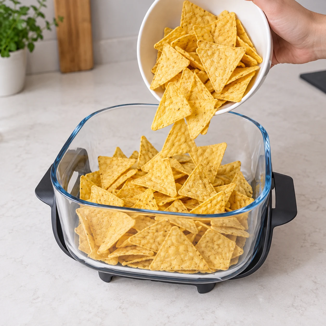 Des chips de tortilla nature versées dans un récipient en verre carré.