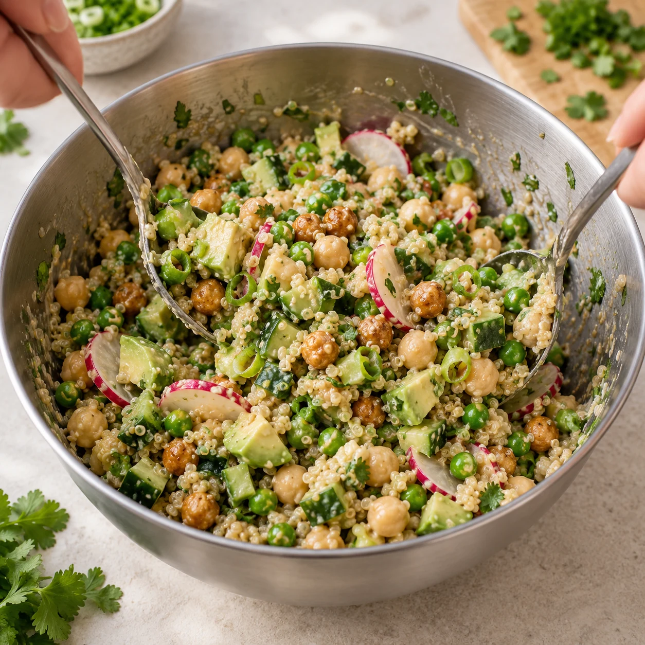 Dans un saladier, mélange le quinoa cuit, le concombre, l’avocat, les pois chiches rôtis, les pickles de radis, les 100 g de petits pois, les 250 g de pois chiches cuits égouttés, la cébette, la coriandre et la sauce.