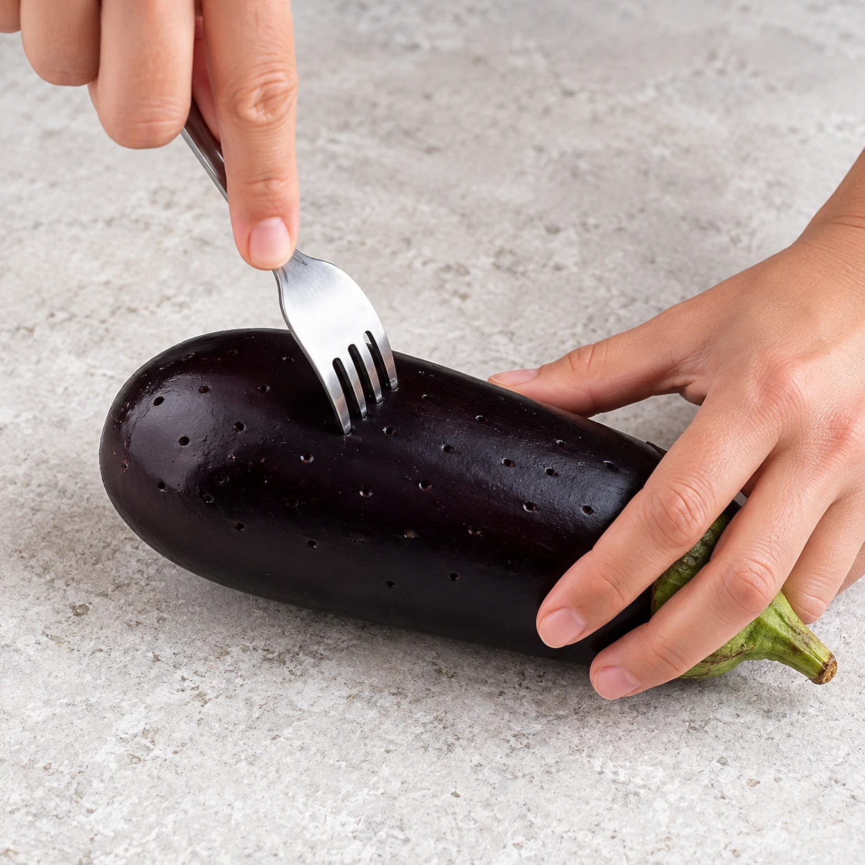 Piquez la peau de l’aubergine avec une fourchette, en la maintenant sur le plan de travail. Montrer une seule phase de préparation, sans texte et sans personne identifiable.