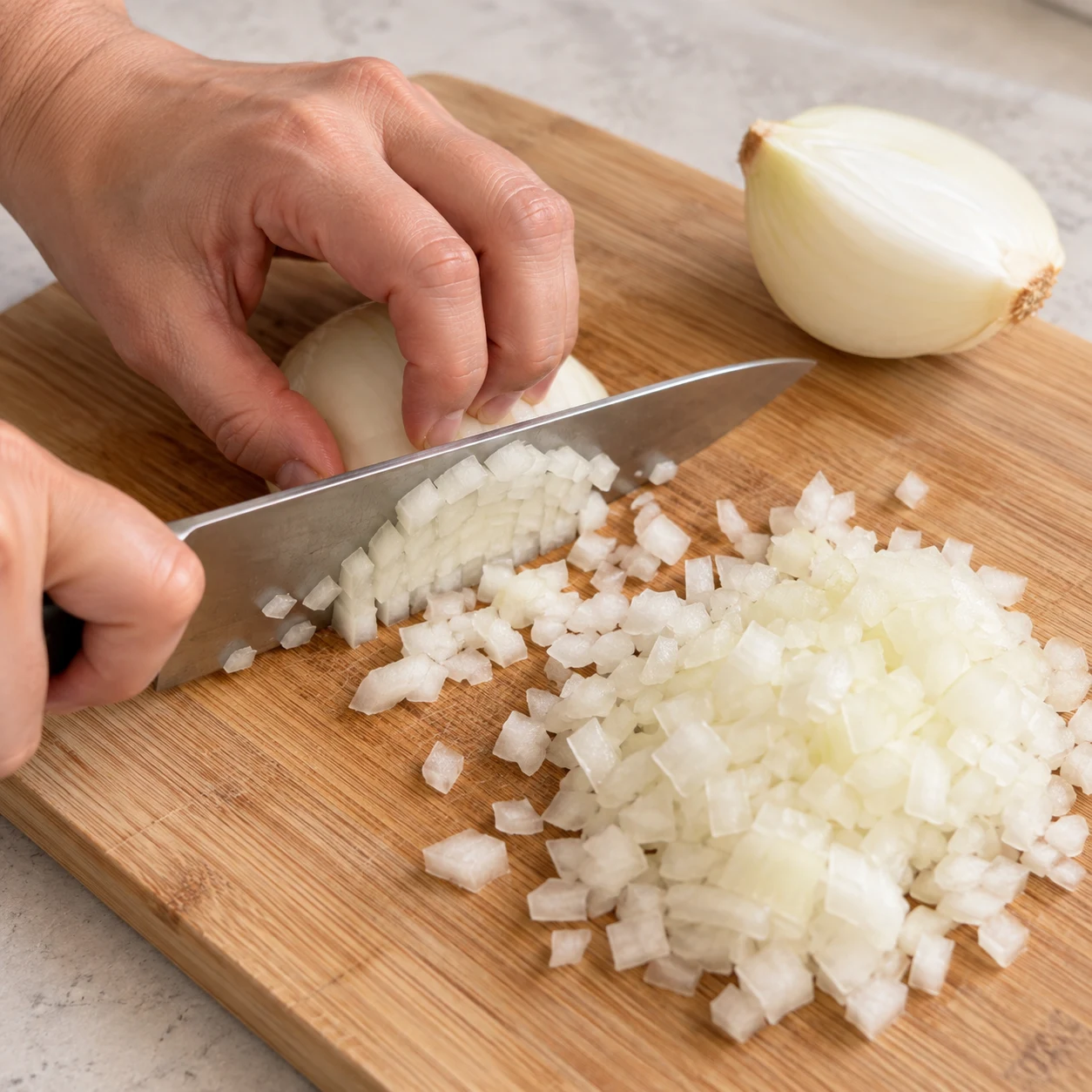 Hachage fin d’un oignon blanc, couteau et prise en griffe.