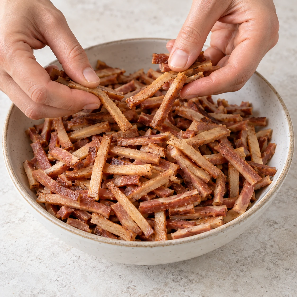 Préparer les lardons végétaux : Sors les 650 g de lardons végétaux fumés de leurs emballages et sépare délicatement les allumettes. Repère final : Les allumettes végétales sont séparées et prêtes à poêler.