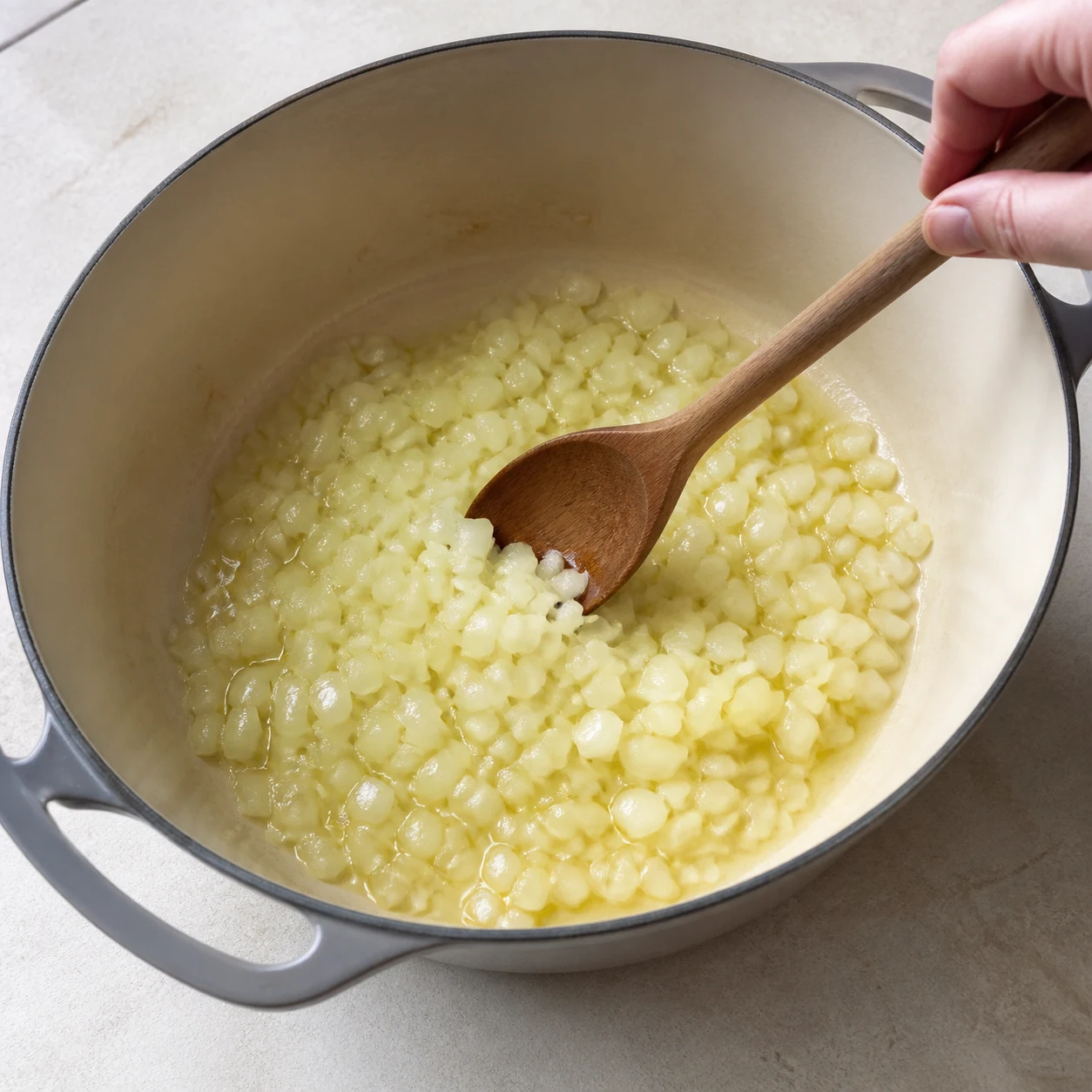 Grande cocotte avec oignons translucides et rondelles de carotte qui reviennent doucement.