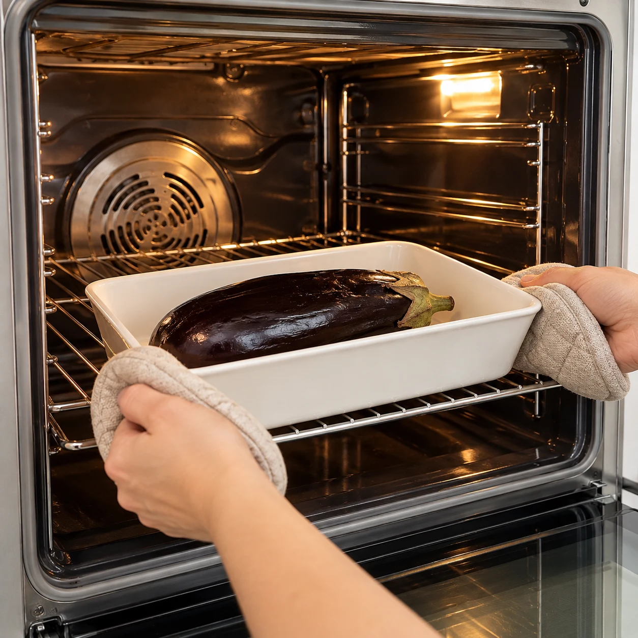Enfournez l’aubergine dans le four préchauffé à 210 °C pendant 40 minutes. Montrer une seule phase de préparation, sans texte et sans personne identifiable.
