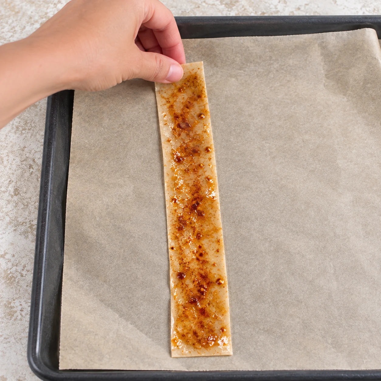 Poser la première bande. Déposez la bande badigeonnée sur du papier cuisson. Résultat : La bande repose à plat sur le papier cuisson. Feuilles de brick fines opaques au blé, jamais de feuilles de riz translucides. Une phase seulement.