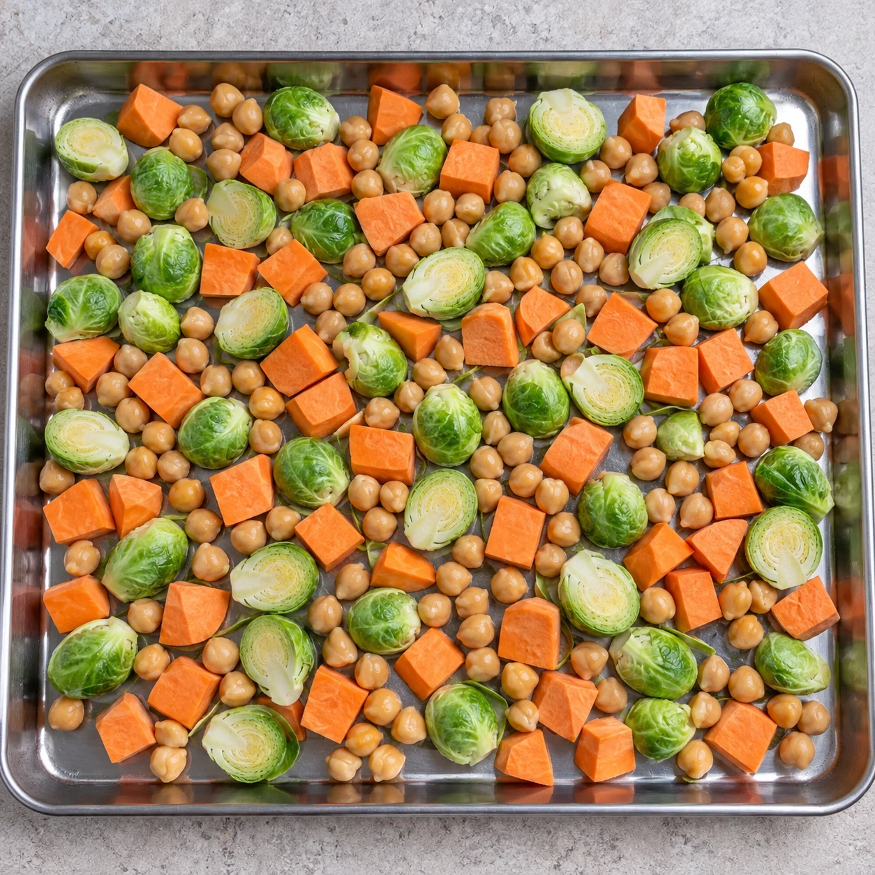Plaque inox : uniquement choux crus coupés en deux, dés de patate douce orange et pois chiches cuits égouttés beige clair, sans marinade.