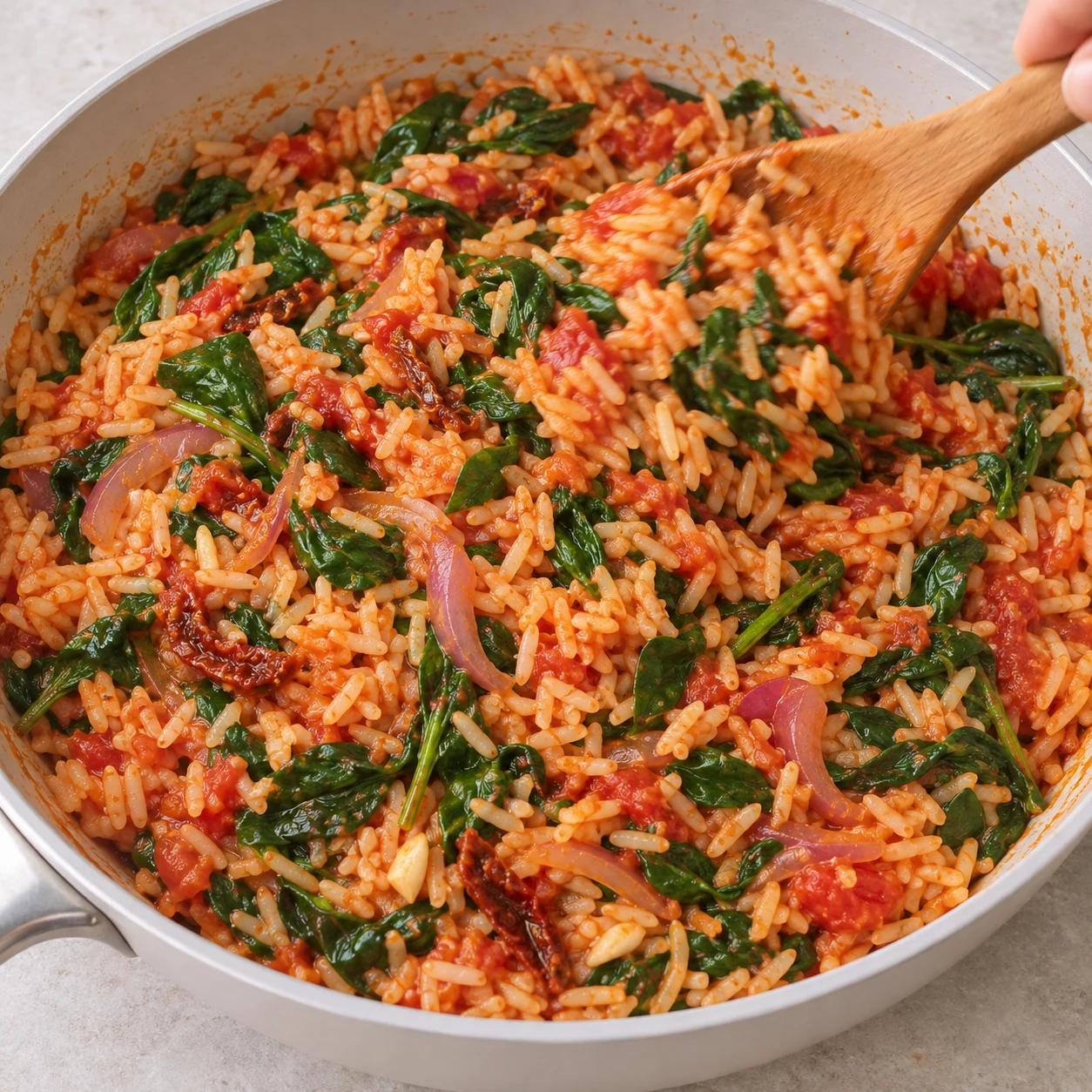 Mélanger la poêlée : Remuez le riz et les légumes jusqu’à ce que les épinards soient réduits et le riz enrobé de tomate.