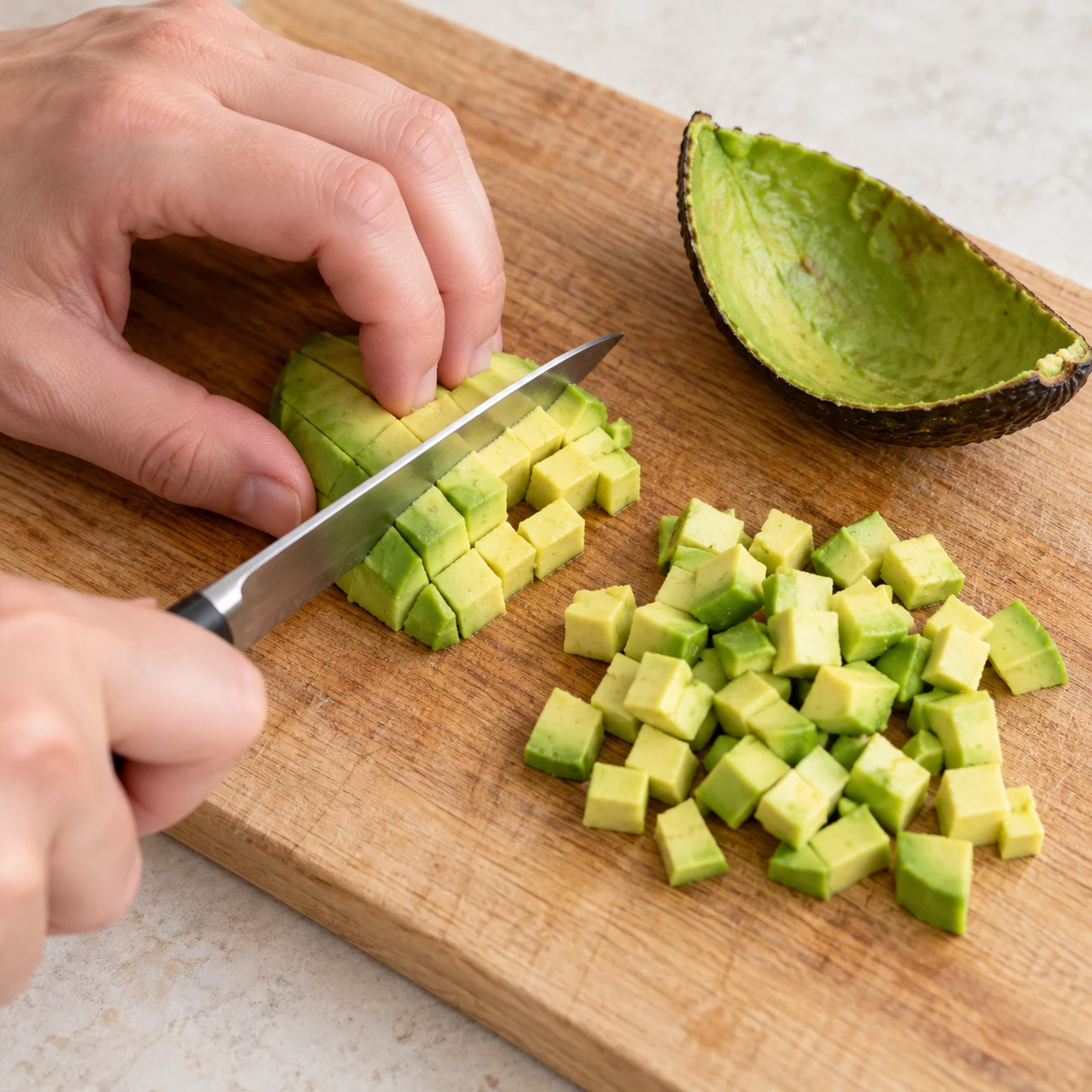 Coupe la chair du quart d’avocat en petits dés sur une planche stable. Montrer seulement les ingrédients de cette étape ; adaptation végétale, aucun saumon ni produit laitier.