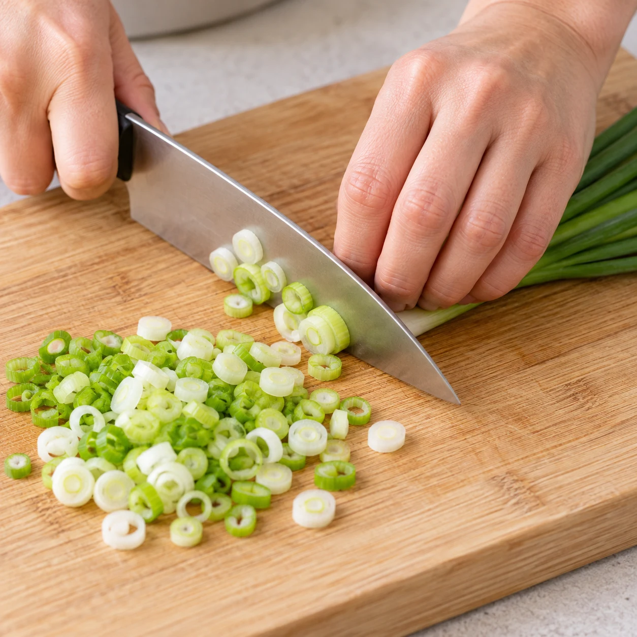Oignon nouveau seul coupé en fines rondelles sur une planche stable, prise en griffe sûre ; la coupe est sourcée par la recette d’origine.