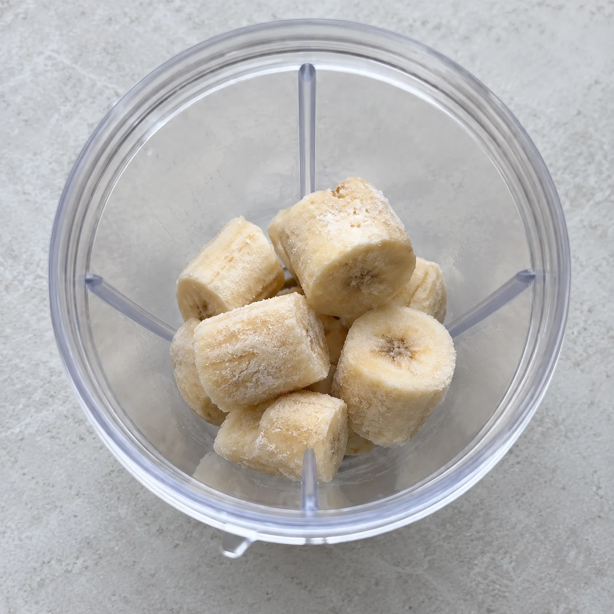 Les morceaux de banane congelée sont dans le bol du mixeur.
