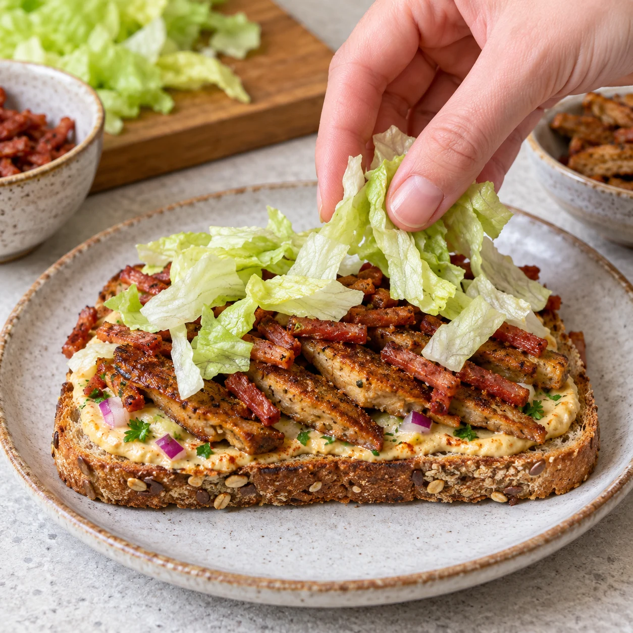 Premier étage ouvert : pain tartiné, steaks végétaux marinés doré, allumettes de lardons végétaux fumés et iceberg.