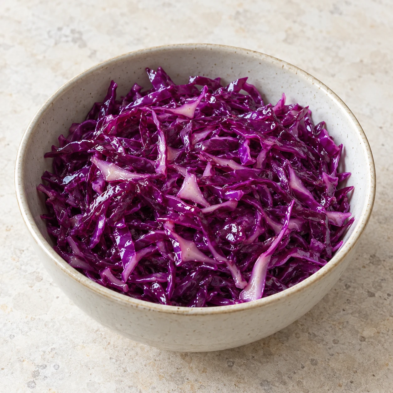 Salade de chou rouge assaisonnée reposant dans son bol ; surface humide et brillante, sans mains ni sésame.