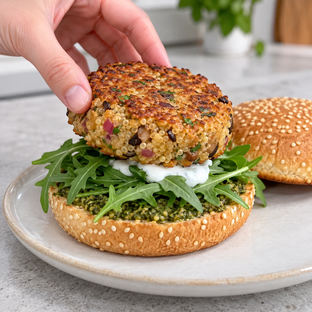 Déposez un steak de quinoa doré sur la garniture de chaque pain. Les pains réellement disponibles sont parsemés de graines de sésame ; ne pas ajouter de sésame ailleurs.