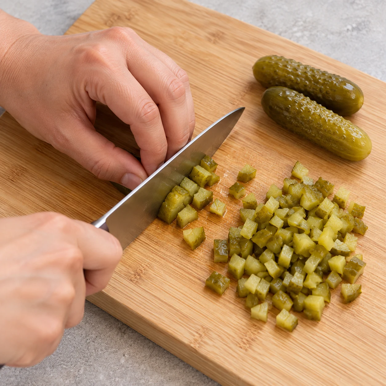 Petits cornichons émincés sur une planche, geste de coupe sûr.