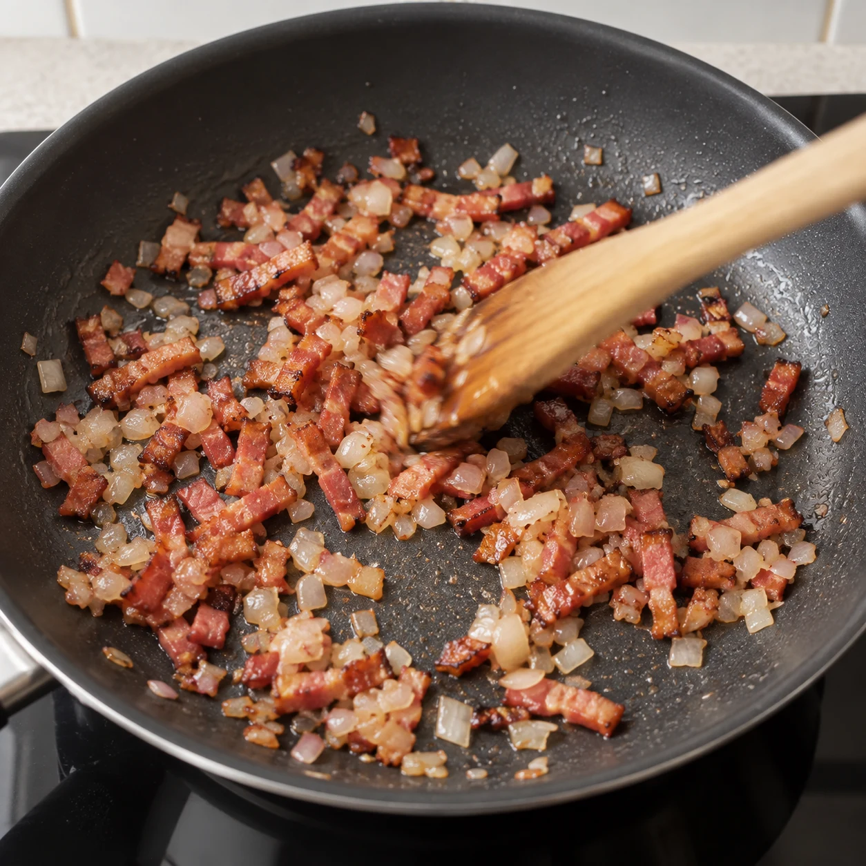 Ajouter l’échalote : Ajoutez l’échalote ciselée aux lardons végétaux et remuez pour la faire revenir. Résultat : L’échalote est translucide et répartie entre les lardons.